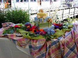orange, rasberry, red roses, sunflowers, hydrangia, freesia, viburnium all surrounding and adorning this package cake